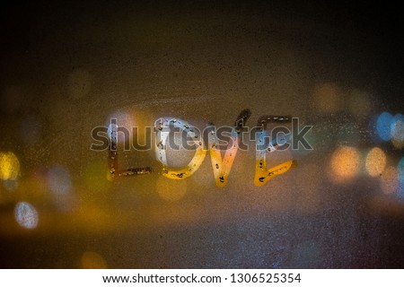 inscription Love on misted glass, night lights bokeh on background