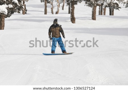Snowboarding on a forest ski slope. White winter mountain landscape. Horizontal