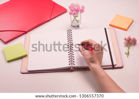 Woman's hand with pen writing somehing at the empty page of notebook