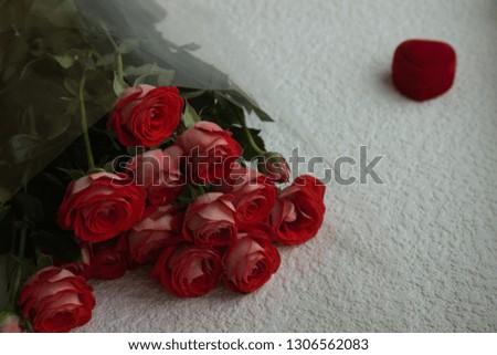 Red roses and a red box in the form of a heart on a white background