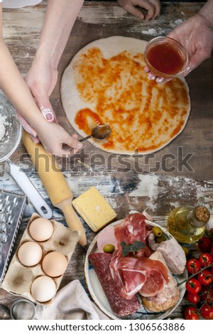 Cooking pizza with mom. Moms and daughters hands cooking homemade pizza together. Ingredients and equipment on the background of the table. Food concept