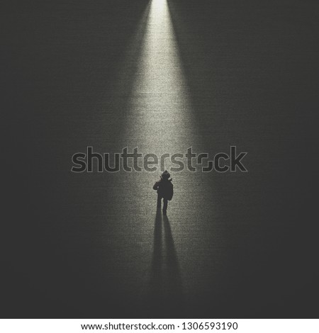 man walking in the night toward a cone of light Royalty-Free Stock Photo #1306593190
