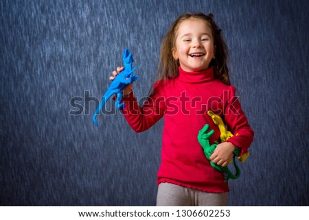 Cute little girl play with toy dinosaurs on the blue background