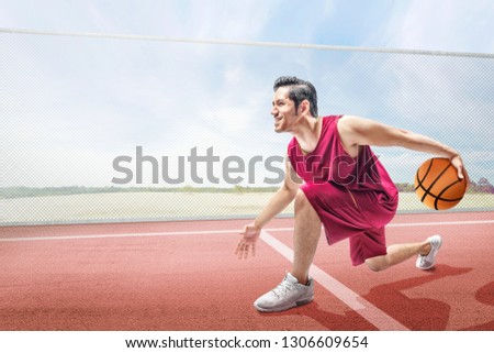 Handsome asian basketball player man playing basketball on the basketball court