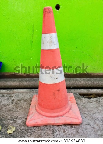 The traffic cone is outstanding in green wall