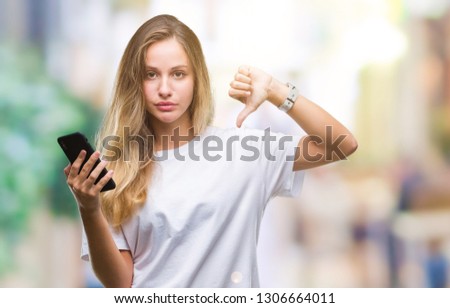 Young beautiful blonde woman using smartphone over isolated background with angry face, negative sign showing dislike with thumbs down, rejection concept