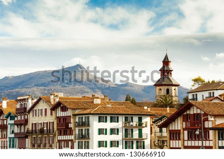 View of the famous Rhune mountain, at the foreground, the Ciboure harbor's bells tower and some typical bask buildings. Royalty-Free Stock Photo #130666910