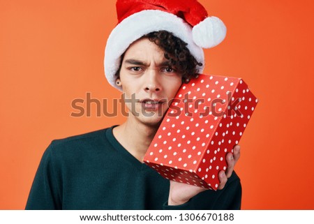 The guy in the red cap from the gift box in his hand on an orange isolated background                      