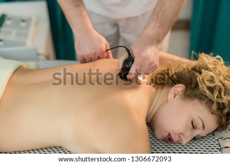 Female patient having back pain so the Masseuse is giving her electrostimulation massage