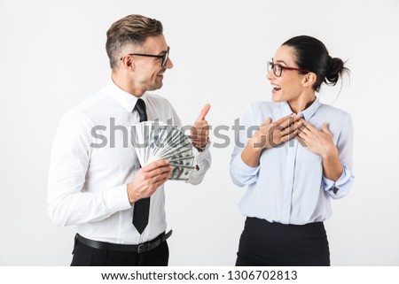 Couple of colleagues wearing formal clothing standing isolated over white background, holding money banknotes