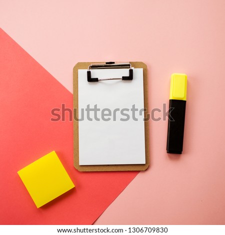 Working space with notepad, eraser and yellow highlighter marker. Pink and coral  background. Empty space for text and design. Office or school concept.   