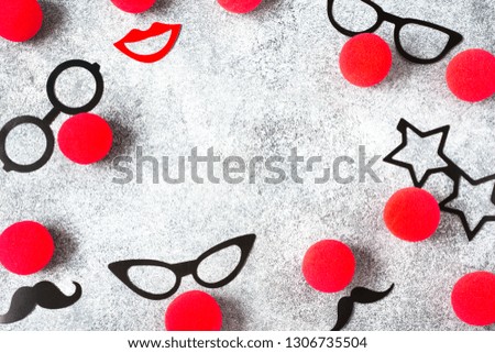Red Nose Day, red noses with glasses, moustache on grey background. Toned deep negative.