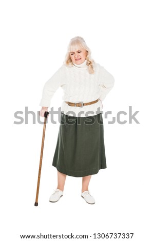 senior woman holding back while having arthritis pain and standing with walking cane isolated on white