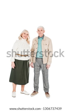cheerful retired couple standing and smiling isolated on white