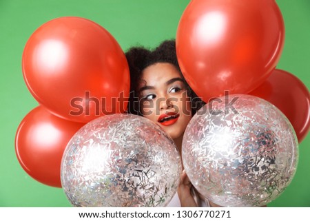 Image of a pretty young african woman posing isolated over green wall background with balloons.