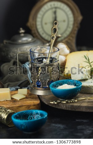Few different kind of cheeses with olives paper and olive oil on black chalkboard in kitchen