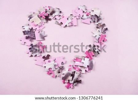 heart made from the puzzle on the pink background