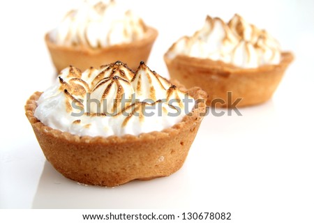 Three lemon tarts with meringue and fresh mint leave on natural tablecloth