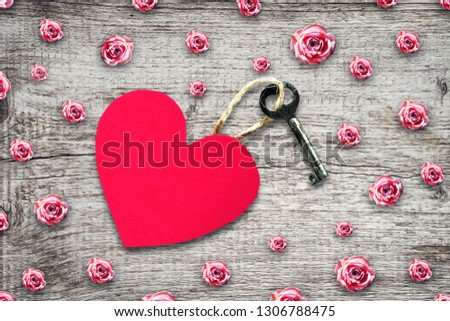 Old key with a tag out of paper heart on a wooden table. Copy space. Top View. Valentine's day background. Festive background.