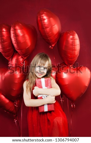 Happy little girl with red balloons and birthday gift on balloons party celebration background. Pretty child birthday party lifestyle portrait