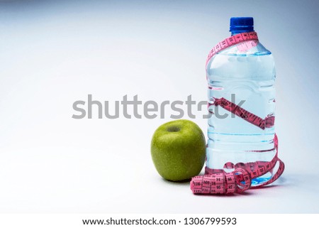 A bottle of mineral water with a centimeter and an Apple. The concept of healthy eating and fitness.