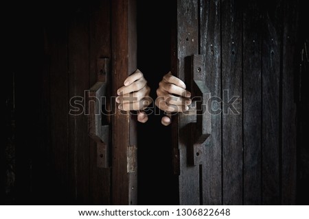 Hands open the wooden door from the inside of the dark room. Royalty-Free Stock Photo #1306822648