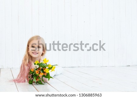 Little beautiful child girl with bouquet of bright colors on white wooden background