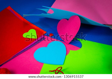 Hearts cut out of bright color foam sheets viewed in full frame background. Bright green and red hearts on blue sheet viewed from above. Love and relationship Valentines Day and color trends concept