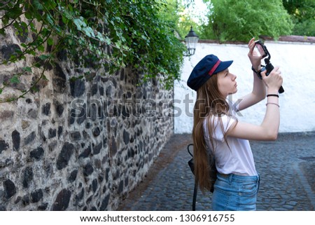 The girl photographer looks for a good angle for taking pictures on the street.