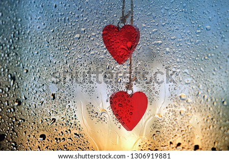 red hearts and rainy drops on glass close up. beautiful atmospheric rainy background. wet window glass texture. symbol of love,  valentine's day concept.