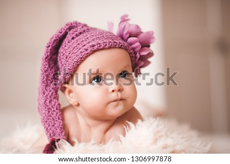 Funny baby girl wearing knitted hat lying in bed closeup. Looking up. Childhood. Good morning. 