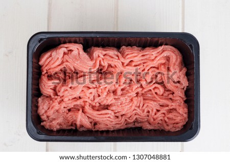 Minced meat in black plastic container. Studio Photo