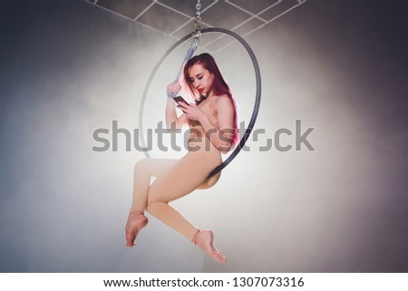 Aerial acrobat in the ring. A young girl performs the acrobatic elements in the air ring. uses the phone to prepare a photo shoot