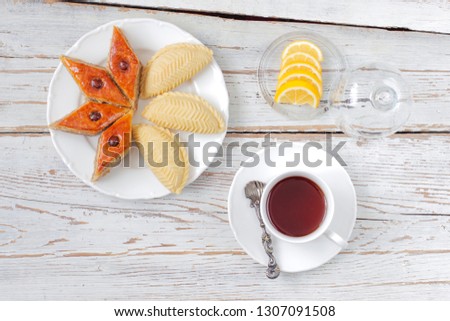 Traditional Azerbaijan holiday Novruz cookies baklava on white plate on the white background with nuts and shakarbura,tea,lemon,kata,mutaki,flat lay,top view,space for copy 