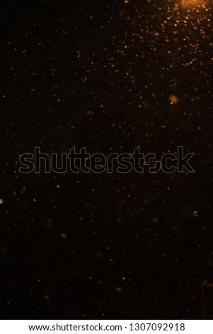Night dark sky and snow flakes. Night landscape. Falling snow in the light of street lamps at night. Blurred snowflakes abstract background. Soft focus and beautiful bokeh.