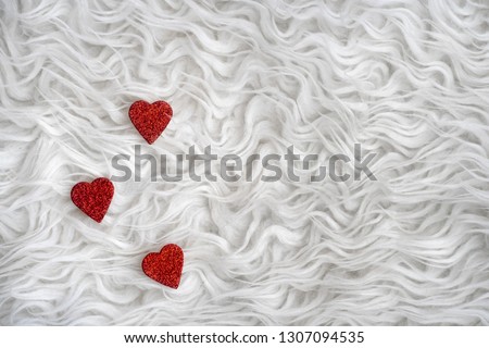 Three red hearts on a white sheepskin