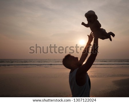 Father throws his baby girl in the air. Silhouette of playing dad and his delighted daughter on the background of the sea sunset. Father's day, loving family, happy childhood, happy fatherhood concept