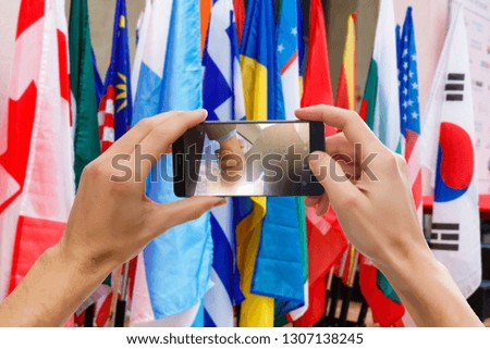 The hands of men make a phone photograph of the flag