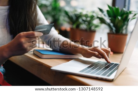 Close up woman's hand holding credit card using laptop computer for online shopping with cash back, discount sales, low prices. Online store concept. Female planning travel and booking tickets. Royalty-Free Stock Photo #1307148592