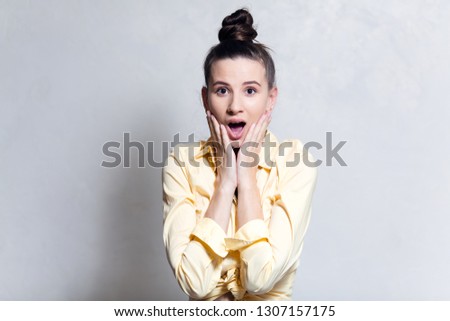 Portrait of young surprised girl hold cheeks by hands over white background.