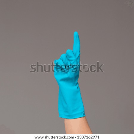 Hand in rubber glove points upwards with index finger. Neutral background , copy space.