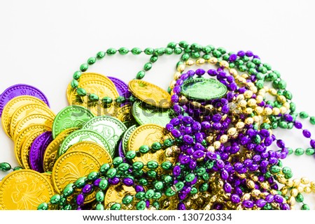 Multi color Mardi Gras beads and tokens on white background.