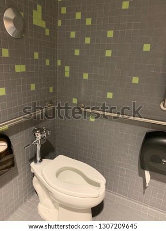 Public restroom with toilet and random pattern tiles in yellow and gray