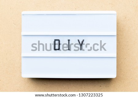White lightbox with word DIY (abbreviation of do it yourself) on wood background