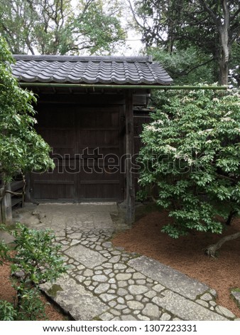 Stone pathway to large gate with black clay ceiling tiles in Kyoto Japan