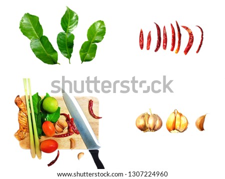 Ingredients for spicy Thai soup Tom Yam isolated on white background with kaffir lime leaves, Chili pepper, tomato, garlic, galangal and lemon which put disrupted on white butcher block.