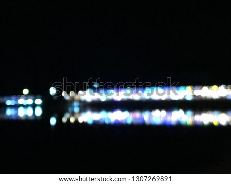 blurred bokeh photography of shopping buildings when turn on the lights in night time with its blue shadow reflects on lake surface, using as background