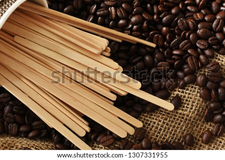 A top view image of several wooden stir sticks and roasted coffee beans.  Royalty-Free Stock Photo #1307331955