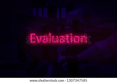 Neon word evaluation, on desktop background. A man works at the computer