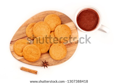 Ginger biscuits with a mug of hot chocolate, a cinnamon stick, and an anise star, shot from above on a white background with copy space